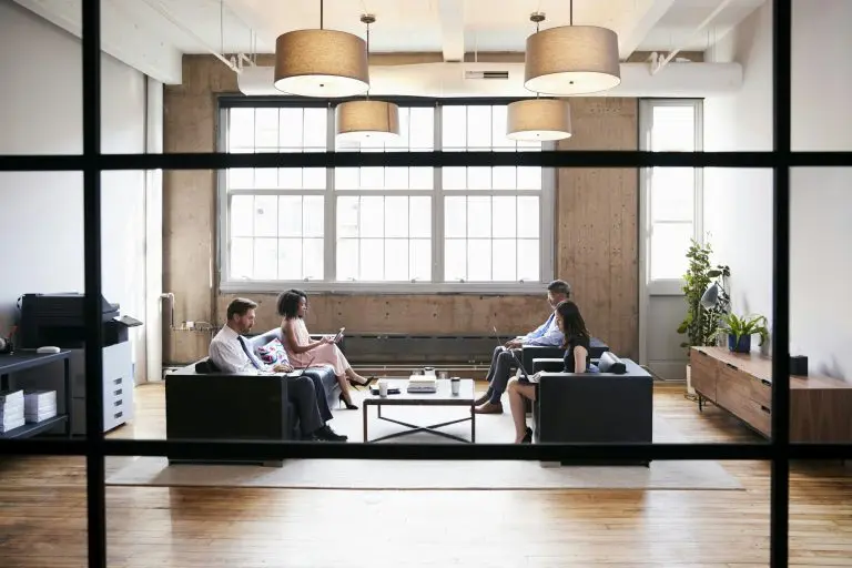 Business people in lounge meeting area, seen through window