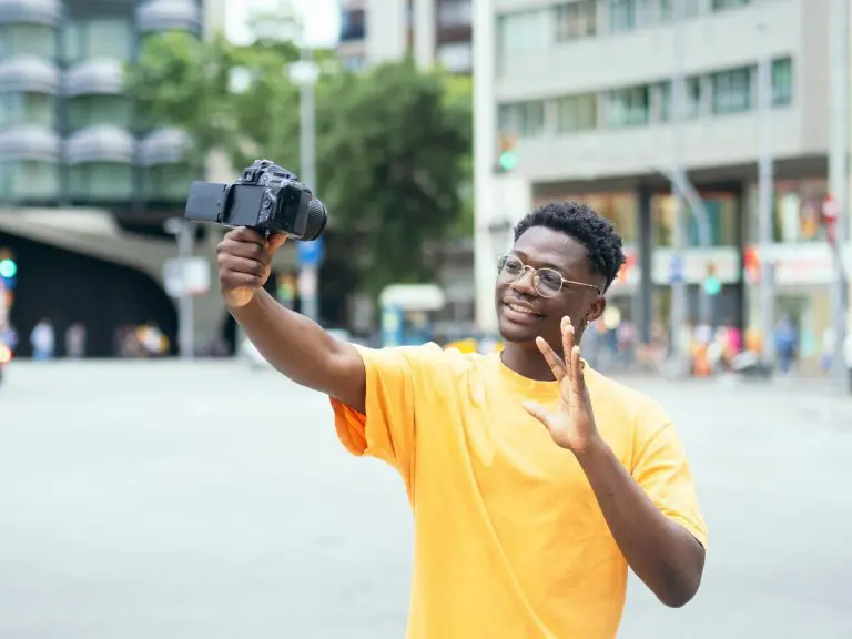 Young African American man recording himself on a video camera in a city