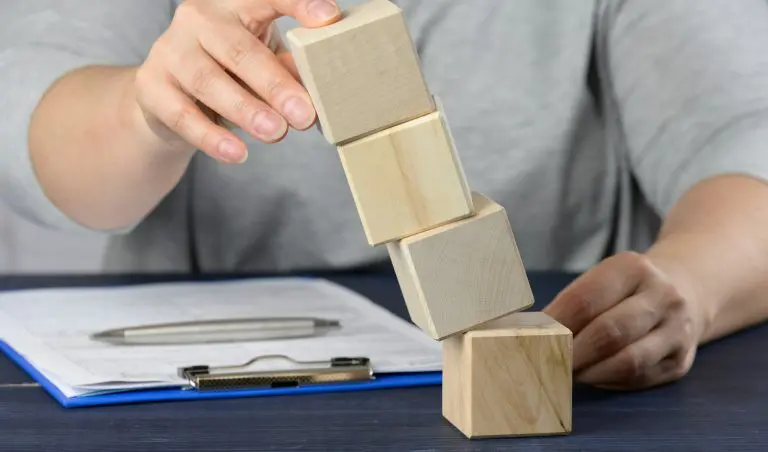 Female hand holds falling cubes on the table. The concept of a manager's crisis