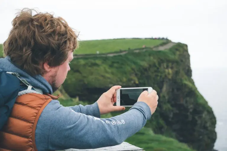 Young man millennial using smartphone at Moher Cliffs